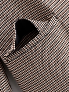 Gros plan sur le motif pied-de-poule marron et les coutures de la poche de la veste de tailleur
