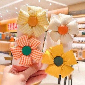Close-up of four handmade fabric flower hair ties in yellow and orange plaid patterns