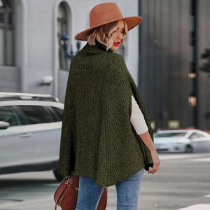 Dettaglio del poncho in maglia verde oliva con collo alto e spacco laterale unico