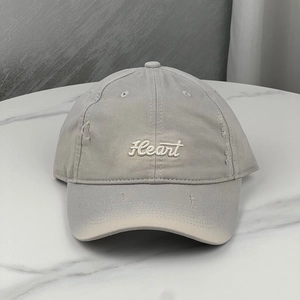 Close-up of distressed cotton baseball cap with Heart embroidery and ripped visor detail