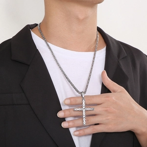 Close-up of a silver cross pendant with vintage geometric patterns on a steel chain