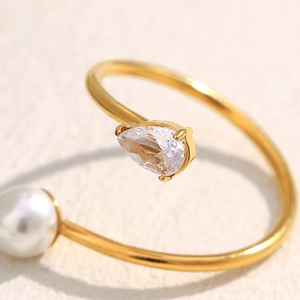 Detailed close-up of an 18K gold-plated ring with a teardrop zircon and white pearl accent
