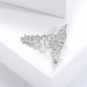 Macro shot of silver medical caduceus brooch with sparkling crystals on a white stand