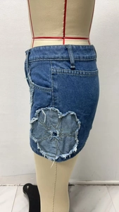 Close-up of denim mini skirt featuring raw edge flower patchwork and distressed details