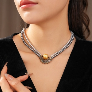 Detail of a vintage double-layer pearl necklace with a gold-tone rhinestone fan pendant