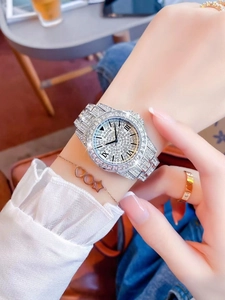 Detailed close-up of a silver rhinestone watch on a wrist with delicate bracelets