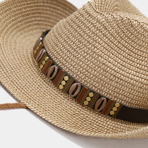 Close-up of woven straw cowboy hat with brown leather band and metallic shell accents