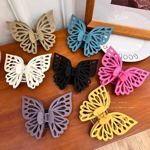 Flat lay of colorful butterfly hair claws in seven matte colors on wooden surface