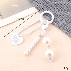 Detail view of a white pearl bow keychain showing 10cm length and 17g weight specs