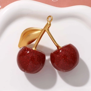 Detail of red glitter cherry pendant with gold leaves on a white ceramic plate