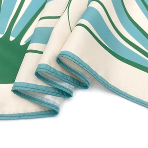 Detailed close-up of premium silk scarf with green twill pattern and fine rolled edges