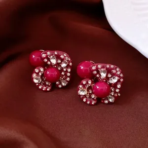 Orecchini a fiore rosso scuro vintage con perle e cristalli su sfondo di seta