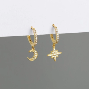 Close-up of asymmetric gold star and moon drop earrings with micro-pave cubic zirconia
