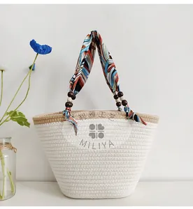 Detail of woven straw tote bag featuring wooden beads and a colorful ribbon handle detail