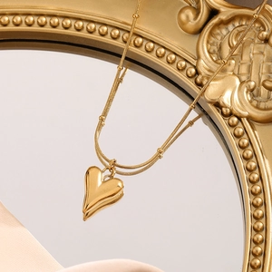 Luxury gold heart pendant necklace with beaded chain on vintage mirror background