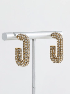 Detail shot of 18K gold plated U-shaped earrings with shimmering crystals on a stand