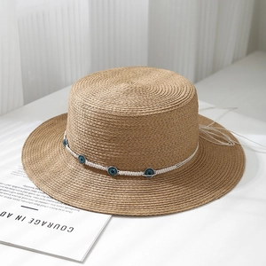 Detailed weave texture of flat-top boater hat with blue evil eye beads and white rope