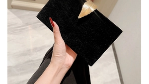 Detail of elegant black velvet evening clutch with a golden leaf metal clasp decoration