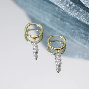 Detailed mirror view of golden hoop earrings featuring three elegant vertical pearls