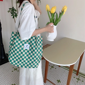 Detail of green and beige checkered corduroy tote bag with 'You need this one' patch