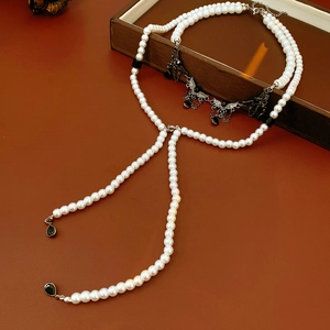 Close-up of pearl wing necklace with black metal tassels and waterdrop pendant details