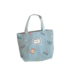 Borsa tote in tela azzurra con ricami di farfalle colorate e toppa decorativa centrale