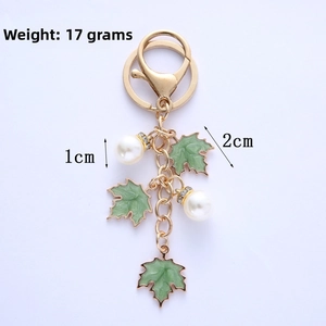 Detail of green enamel maple leaf and pearl keychain with gold-plated metal chain