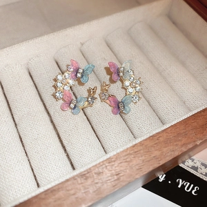 Détail de boucles d'oreilles papillon en C avec strass et perles sur velours