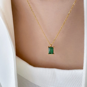 Detail shot of rectangular emerald green gemstone pendant with a delicate gold chain
