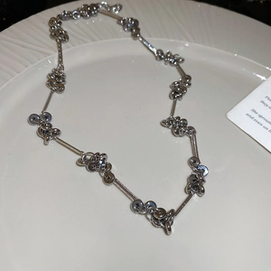 Macro shot of silver link necklace with circular charms on a white ceramic plate