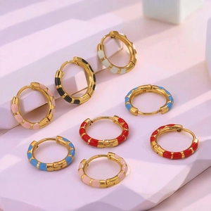 Colorful enamel huggie earrings in gold plated stainless steel on geometric display