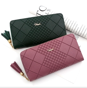 Detail of dark green and mauve long wallets with quilted texture and tassel zipper
