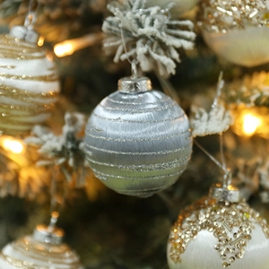 Close-up of silver striped Christmas ball ornament with glitter on a festive tree branch
