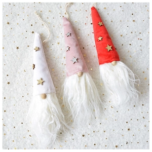 Three plush Christmas gnome hanging ornaments with golden stars on snowy background