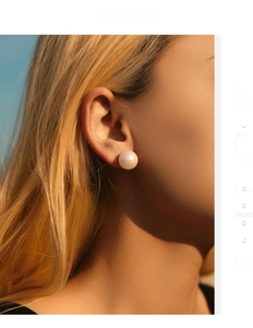 Close-up of large round white pearl stud earring worn by model in natural sunlight