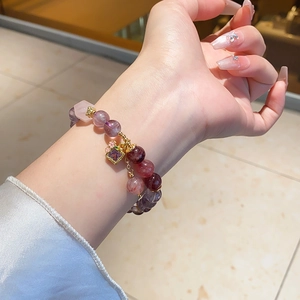 Detailed close-up of amethyst beaded bracelet with zircon pendant on a woman's wrist