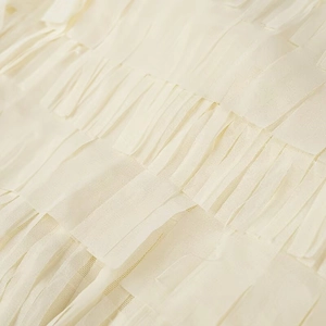 Detailed close-up of layered beige fringe design on lightweight long sleeve shirt fabric