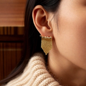 Gros plan de boucles d'oreilles dorées à pampilles portées par un mannequin en douceur