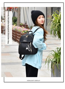 Detail of black oxford backpack with gold zippers and cute bear charm for travel