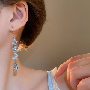 Close-up of long blue butterfly earrings with a faceted crystal drop on a female model