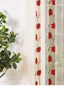 Detail of beige sheer curtain with red floral embroidery and green potted plant decoration