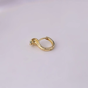 Macro shot of gold-plated snake-shaped earring with green stone eye details
