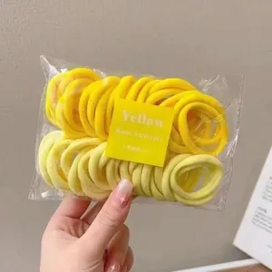 Detailed view of 50 yellow high-elastic hair ties in transparent packaging with card