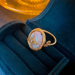 Anello con perla barocca, filo dorato e zircone su scatola di velluto blu