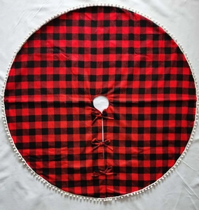 Detail eines rot-schwarz karierten Weihnachtsbaumrockes mit weißen Pompons am Rand