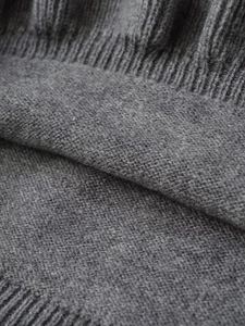 Macro shot of gray knitted fabric texture showing soft ribbed edges and weave patterns
