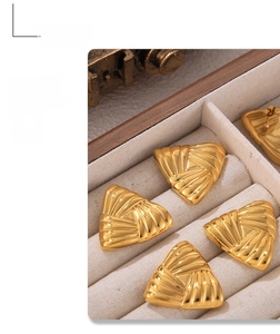 Macro detail of golden geometric triangle earrings with textured surface in jewelry box