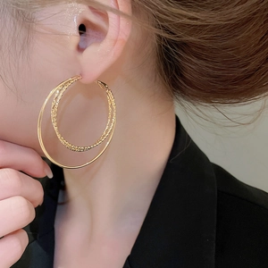 Close-up of 18k gold plated double hoop earrings worn by a model in soft lighting