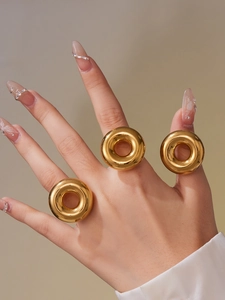 Detailed view of three thick gold plated hollow circle rings on model's hand