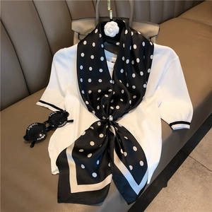 Close-up of black and white polka dot silk scarf with elegant pearl buckle detail